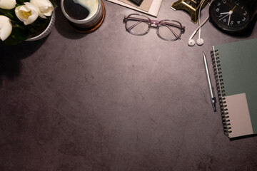 Top view glasses, coffee cup, notebook and flower pot on dark stone background with copy space.