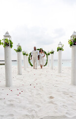 Maldives Wedding with Bride and Groom walking down the sandy aisle after getting married