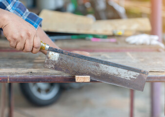 Close up the mand use hand saw cutting wood stick.