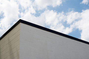 The corner upward view of an exterior wall of a concrete block building.  The wall is made of grey...