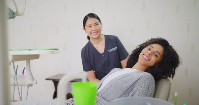 Orthodontist and patient smiling with perfect teeth in consultation office. Woman feeling confident with her oral whitening service appointment at a healthcare clinic or private practice