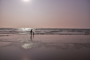 Son holds hand of his father while watching sea wave closely.