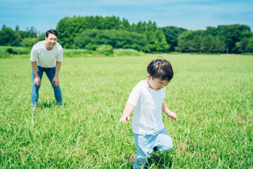 草原を走る男の子と見守る父親