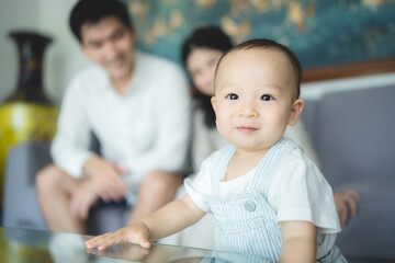 Obraz premium Playful young mother playing with toddler baby sitting on father lap on couch at home
