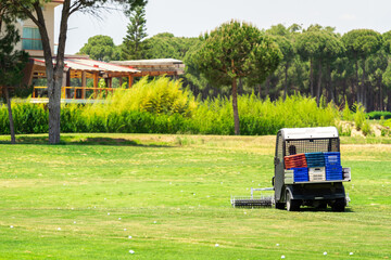 Golf course and a vehicle collecting golf balls. Ballpicker on driving range of golf club