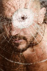 Portrait of stranger man. Gangster man. Dangerous criminal, hooligan guy on cracked bullet glass.