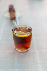 A glass of hot black tea with a slice of lemon on a light tablecloth