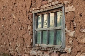 Fototapeta na wymiar The texture of the clay wall of an old house with window