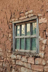 The texture of the clay wall of an old house with window