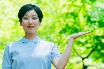 新緑の中、笑顔で笑うポロシャツを着た日本人女性