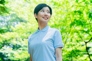 新緑にいるポロシャツを着た日本人女性