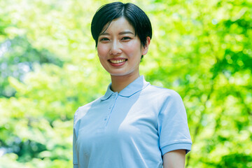 新緑・カメラ目線のポロシャツを着た日本人女性