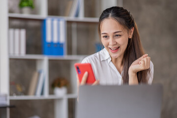 Happy Asian young woman waving hands looking at web camera using phone for video call at home, smiling business woman having fun greeting online by phone webcam making video call via application