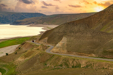 landscape with mountains, road and lake in sunset