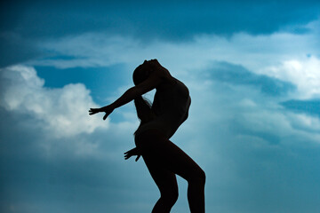 Silhouette of fitness sport woman stretching out before training. Female fit model. Stretching and motivation. Dance studio. Cloudy sky background.