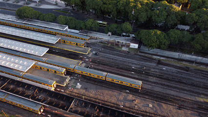 Aerial top view over yellow train departing at Federico Lacroze station in Buenos Aires
