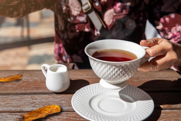 female hand holding a hot cup of  tea in autumn morning