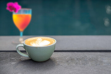 a cup of hot coffee latte art beside pool