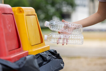 Hand of human pouring plastics bottle to recycle bin color yellow It is a trash bin that separates...