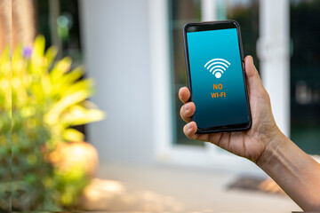 Woman's hand holding a phone, and tries to find a signal wifi On the phone screen, the symbol with...