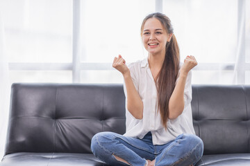 Excited young Asian woman on sofa in home office