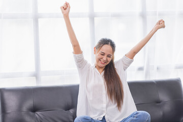 Excited young Asian woman on sofa in home office