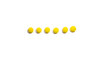 six yellow round candies are laid out in a line on a white background