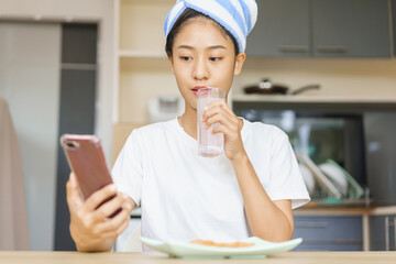 Home lifestyle concept, Young woman in turban after shower to drinking water and surf social media