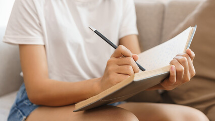Home lifestyle concept, Young woman sitting on couch to taking notes on notebook at home