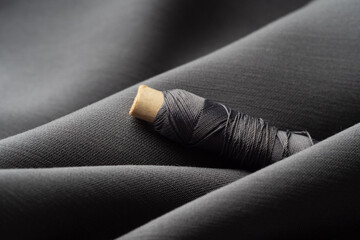 A reel with gray threads in a draped soft fabric, close-up, macro. Atelier, tailoring, sewing...