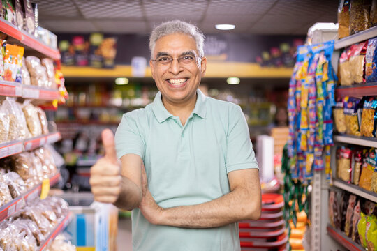 Senior man show thumbs up at grocery store products.