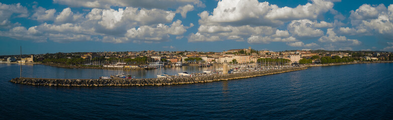 Fototapeta premium Panorama of the city of Desenzano del Garda on Lake Garda in Italy. Aerial view of the coastline of the city of Desenzano del Garda, Lake Garda.