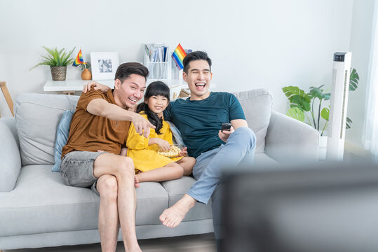 Asian male gay family with young daughter watch movie in living room. 