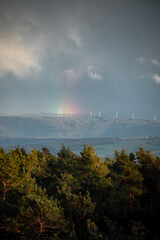 Wind turbines below a stormy sky and rainbow in Germany,Europe. © szaboerwin