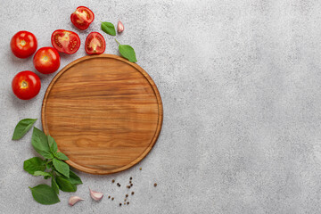 light culinary background with round wooden board, tomatoes and basil