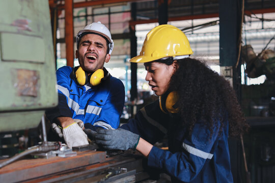 Young technician engineer or worker man in protective uniform had a hand accident on lathe machine in metal lathe factory. Safety colleague team helping him from accident. First aid training concept