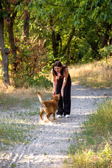 Young beautiful smiling woman walking with her dog  in the woods