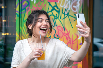 Attractive young woman takes a selfie with a glass of lemonade.