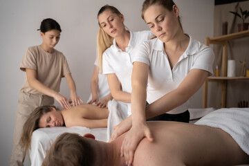Health wellness massage training.Teacher helping student training to become masseuse - obrazy, fototapety, plakaty
