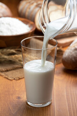 木のテーブルにグラスにはいった牛乳とたくさんのパン