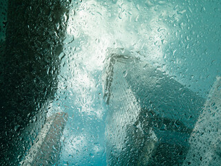 Droplets water on glass window with Building reflection cityscape blur background