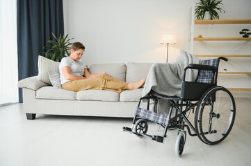 Brunette woman on couch near wheelchair