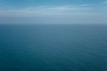 The front view of the sea with morning sky and fuzzy horizon. The ocean deep indigo color in daylight. Feeling calm, cool and relaxing.