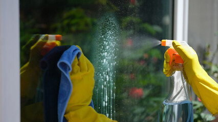 Female cleaner cleaning window using detergent and rag