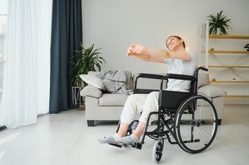 Fototapeta premium Woman in wheelchair working out in living room