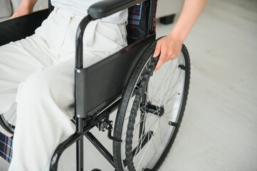 Obraz premium Woman in wheelchair's hand on wheel close up