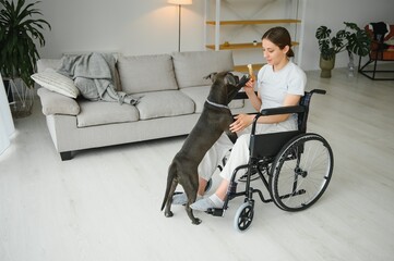 Young woman in wheelchair with dog indoors