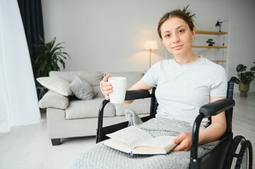 Fototapeta na wymiar Woman in wheelchair reading book at home