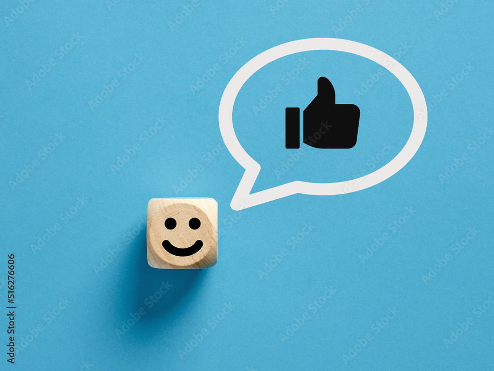 Poster happy face icon on a wooden cube with like or thumb up gesture in a speech bubble.