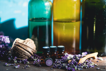 Bottle with aroma oil and lavender flowers on blue background